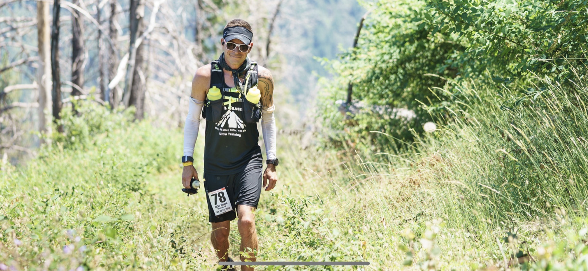 Ricky Roane power-hiking a sun-exposed canyon climb during a hundred-mile race.